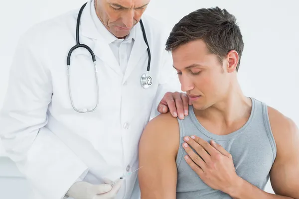 Médico varón inyectando un brazo de pacientes — Foto de Stock