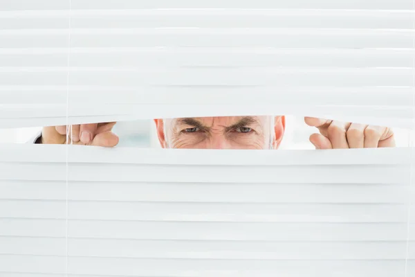 Retrato de perto de um homem de negócios espreitando pelas cortinas — Fotografia de Stock