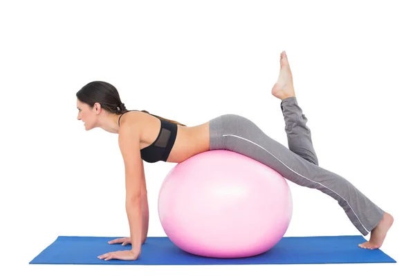 Vista lateral de una mujer en forma estirándose en la pelota de fitness — Foto de Stock
