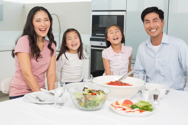 Potret keluarga yang tersenyum duduk di meja makan di dapur — Stok Foto