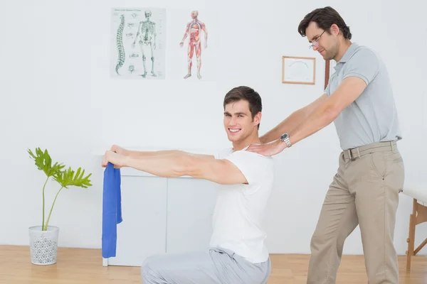 Terapeuta masculino assistindo jovem com exercícios — Fotografia de Stock