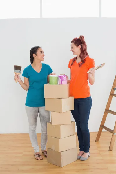 Friends with paint brushes, cans and boxes in a new house — Stock Photo, Image