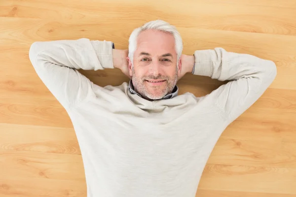 Overhead portrait of a smiling man lying on parquet floor — Stock Photo, Image