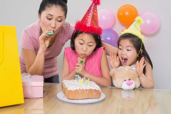 Girls and mother blowing noisemakers at a birthday party — Stock Photo, Image