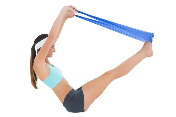 Side view of a fit woman exercising with a blue yoga belt — Stock Photo, Image