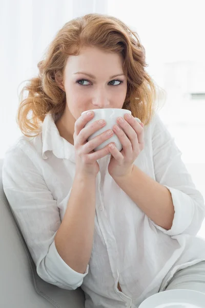 Thoughtful young woman drinking coffee at home — Stock Photo, Image