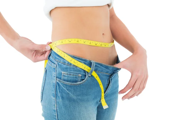 Seção média de mulher medindo a cintura em um jeans de tamanho grande — Fotografia de Stock