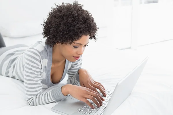 Mujer joven contenido usando el ordenador portátil en la cama — Foto de Stock