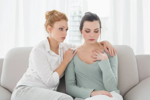 Jonge vrouw troostende vrouwelijke vriend thuis — Stockfoto