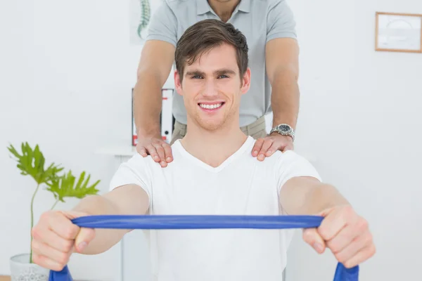 Terapeuta masculino que ayuda al hombre con ejercicios en la oficina — Foto de Stock