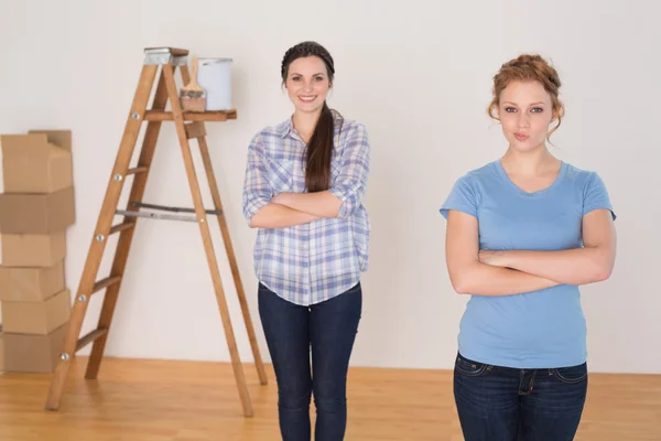 Friends standing with arms crossed in a new house — Stock Photo, Image