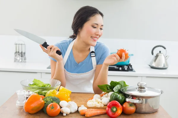 Улыбающаяся женщина режет овощи на кухне — стоковое фото