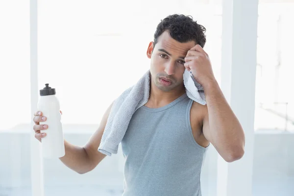 Young man wiping sweat with towel in fitness studio — Stock Photo, Image