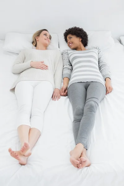 Two casual young female friends lying in bed — Stock Photo, Image