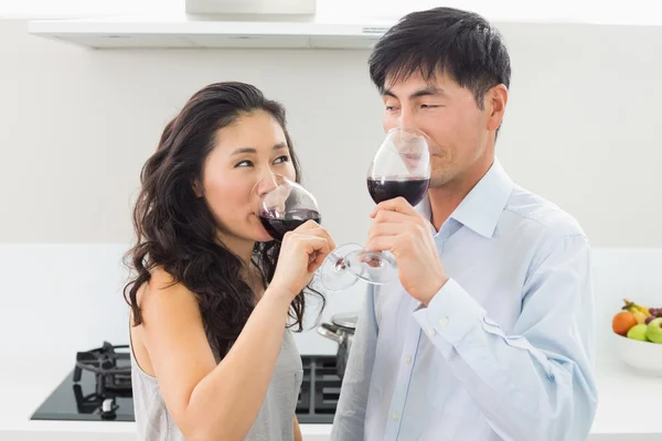 Liefdevolle jong koppel drinken van rode wijn in keuken — Stockfoto