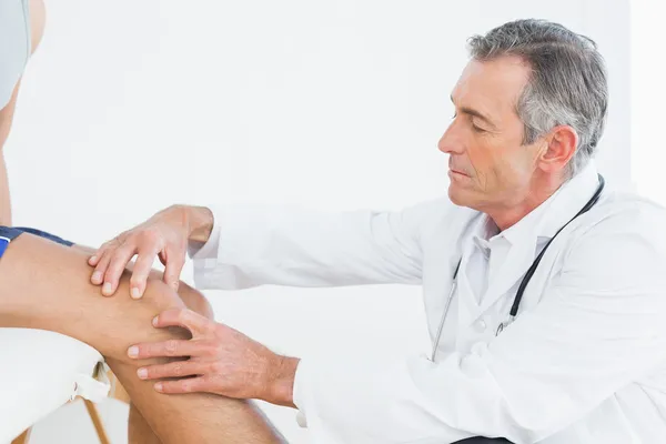 Boční pohled na starší lékař zkoumá pacienti koleno — Stock fotografie