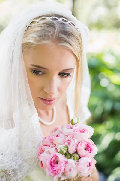 Sposa sorridente che indossa velo sul bouquet di tenuta del viso — Foto Stock