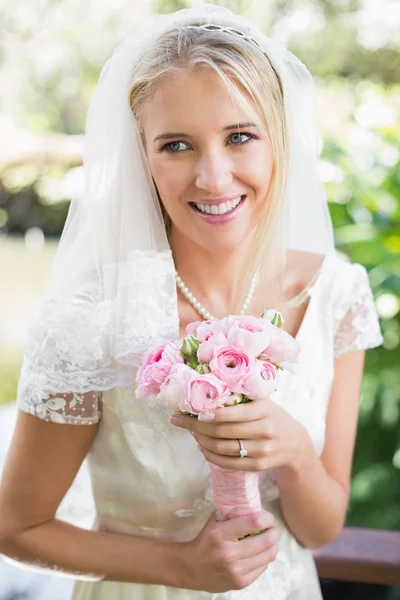 Felice sposa in un velo che tiene il suo bouquet rosa — Foto Stock