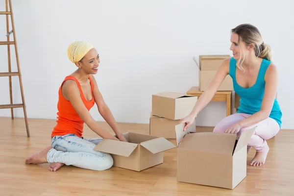 Felices amigos abriendo cajas en una casa nueva — Foto de Stock