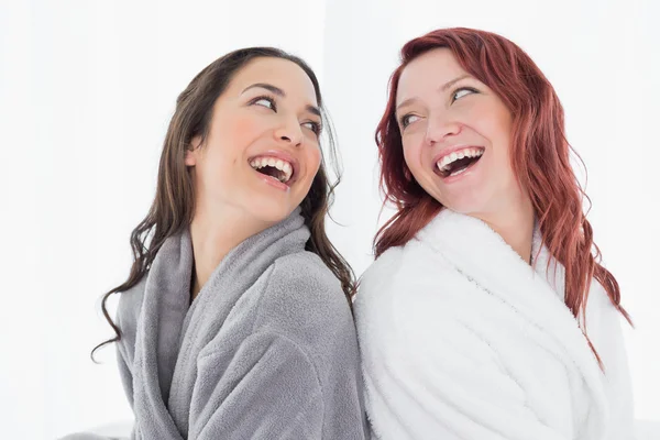 Happy female friends in bathrobes standing back to back — Stock Photo, Image