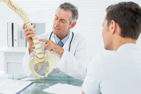 Arzt erklärt einem Patienten im Büro die Wirbelsäule — Stockfoto