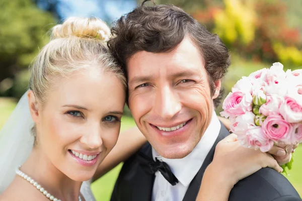 Bride and groom embracing and smiling at camera — Stock Photo, Image