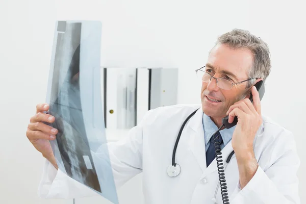 Médico com imagem de raios-x usando telefone no escritório — Fotografia de Stock