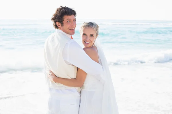 Jeunes mariés debout au bord de la mer souriant à la caméra — Photo