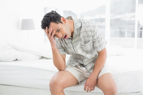 Man sitting and yawning in bed — Stock Photo, Image