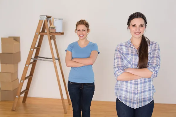 Vrienden permanent met gekruiste in een nieuw huis armen — Stockfoto