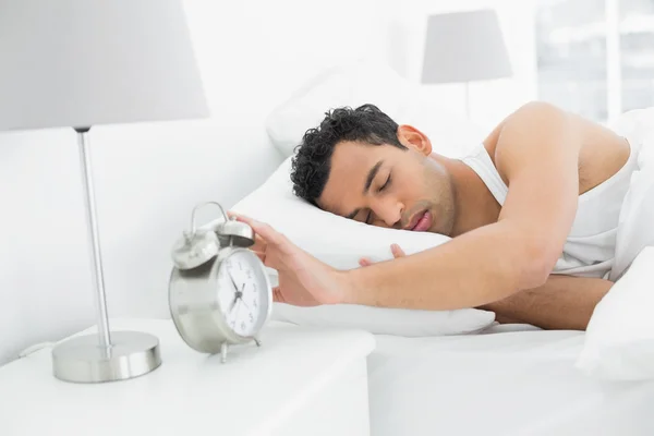 眠そうな男が目覚まし時計に手を拡張します。 — ストック写真