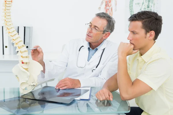 Médico explicando coluna vertebral para paciente no escritório — Fotografia de Stock