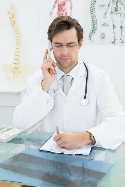 Sorrindo jovem médico do sexo masculino usando telefone — Fotografia de Stock