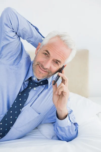 Mogna affärsman med mobiltelefon i sängen — Stockfoto