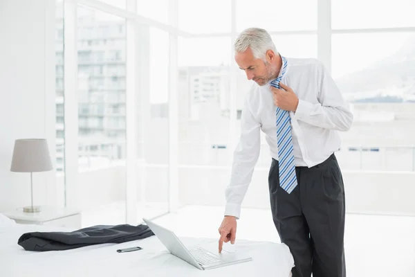 Zakenman stropdas dragen terwijl het gebruiken van laptop op een hotelkamer — Stockfoto
