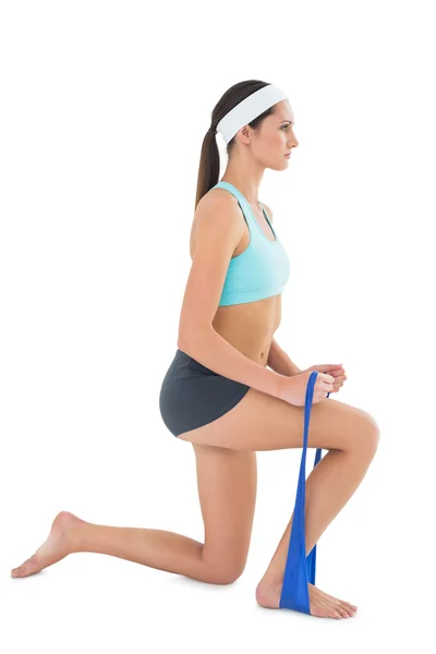 Ajuste mujer joven que hace ejercicio con un cinturón de yoga azul — Foto de Stock