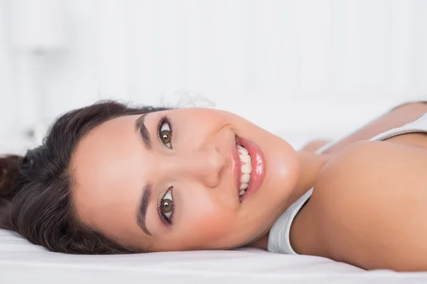 Lachende mooie jonge vrouw ontspannen in bed — Stockfoto
