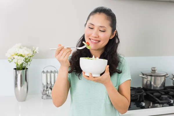 Femme souriante avec un bol de salade dans la cuisine — Photo