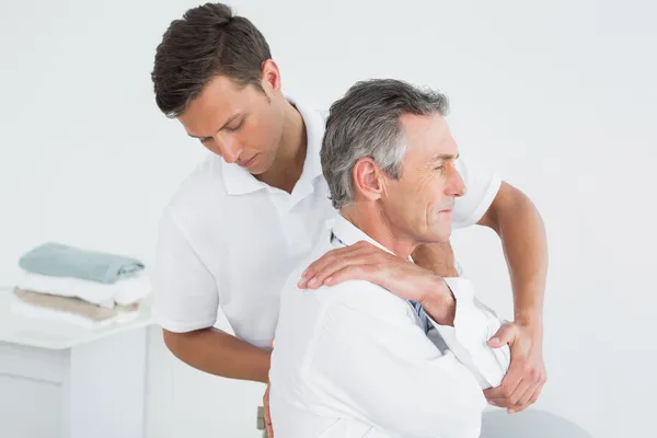 Male chiropractor examining mature man Stock Picture