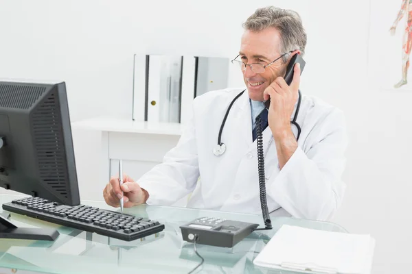 Medico con computer e telefono in ufficio — Foto Stock