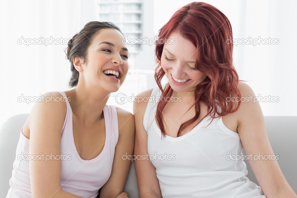 Two beautiful young female friends laughing in living room