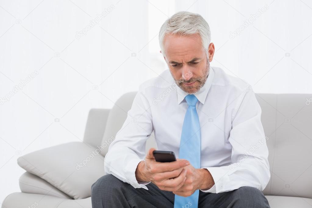 Elegant mature businessman text messaging at home