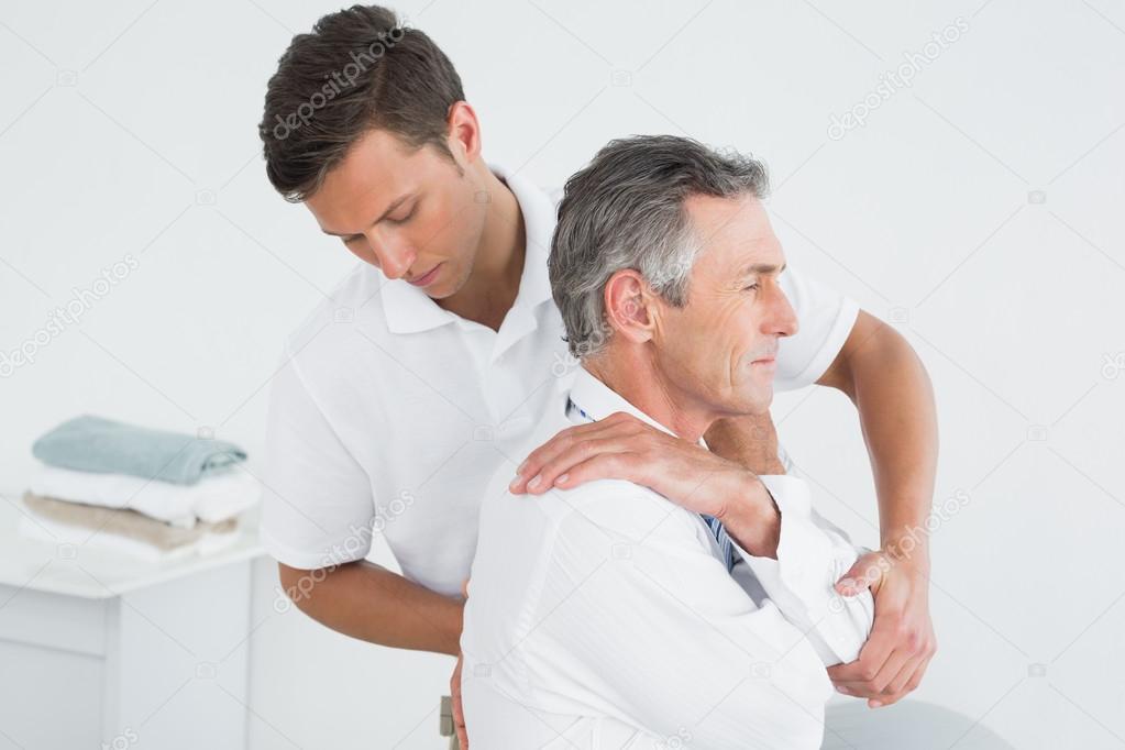 Male chiropractor examining mature man