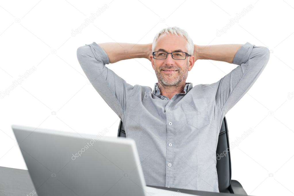 Businessman sitting with hands behind head and laptop