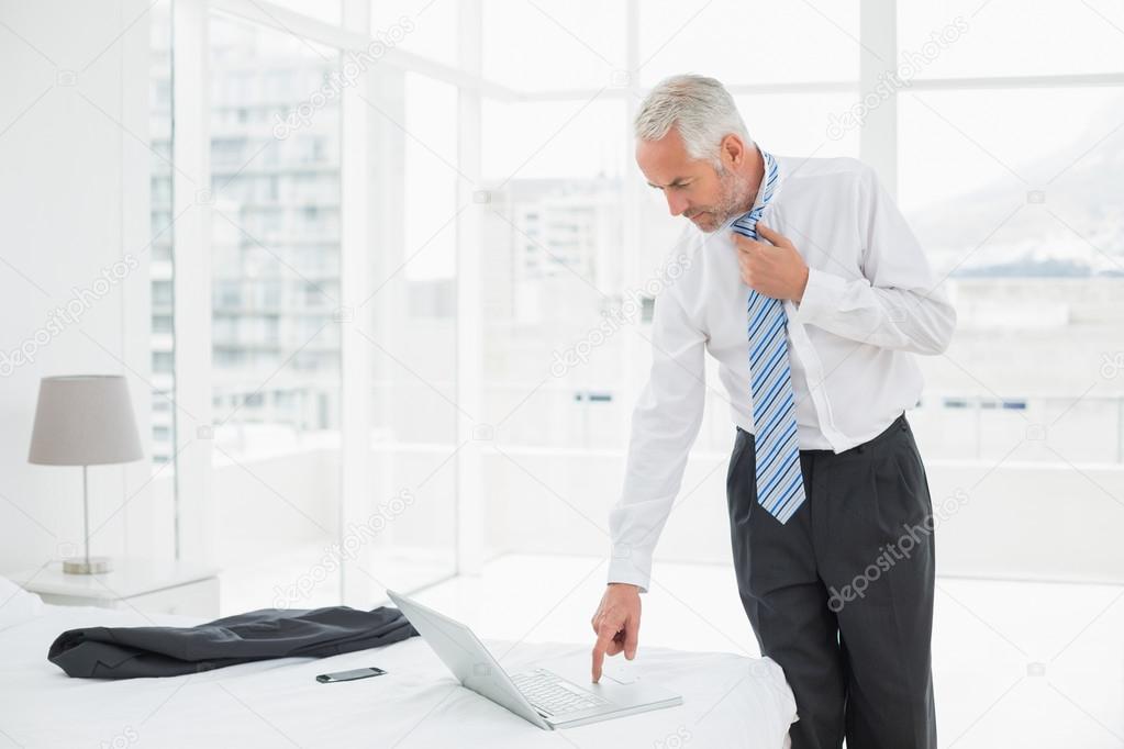 Businessman wearing tie while using laptop at a hotel room
