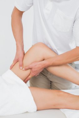 bir kadının bacak inceleyerek erkek fizyoterapist