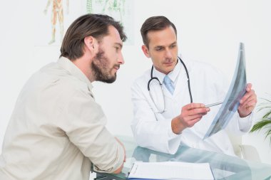 Male doctor explaining spine x-ray to patient
