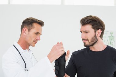 erkek fizyoterapist bir adamın bileğini incelenmesi