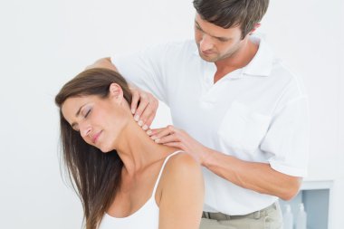 Male chiropractor massaging a young woman's neck clipart