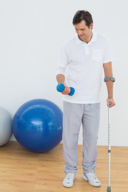 koltuk değneği ve dumbbell ile gülümseyen genç adam